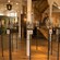 Beer bottles on stands enclosed by glass stand on display in front of beer barrels, historic images and a staircase